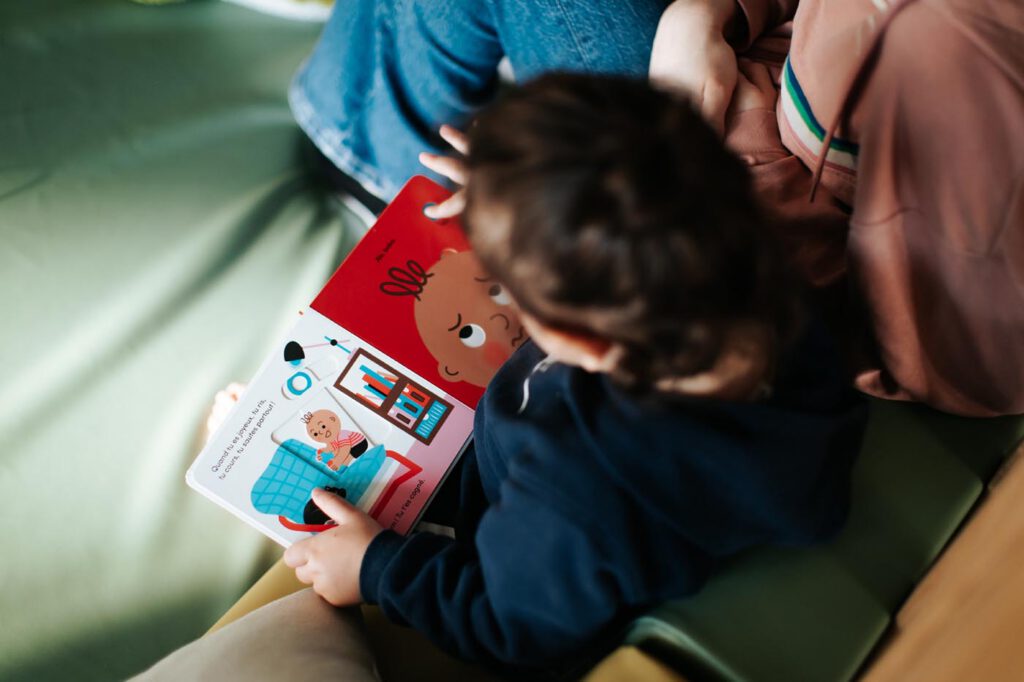 Enfant lisant un livre avec une éducatrice