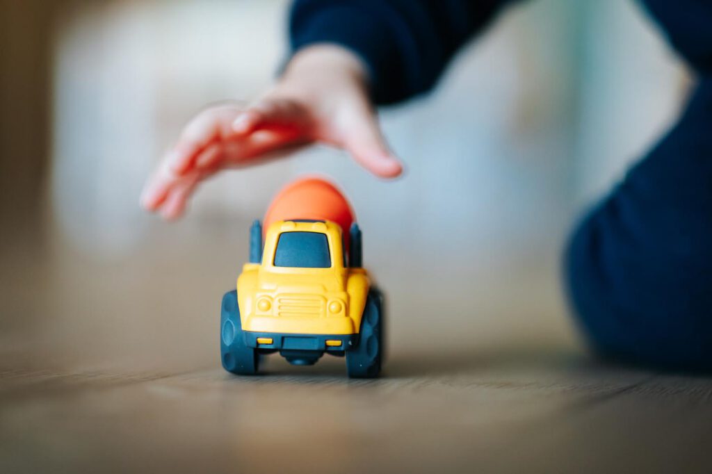 Enfant jouant avec camion jouet jaune et orange